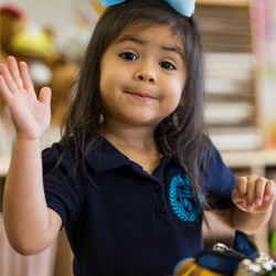 Niña saludando a la cámara con uniforme
