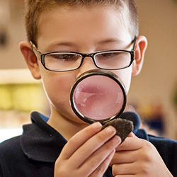 niño mirando a través de una lupa con gafas