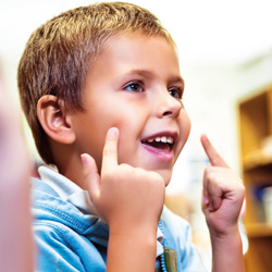 niño sonriendo y señalando a la cara