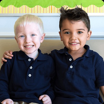 two boys smiling in blue shirts in preschool