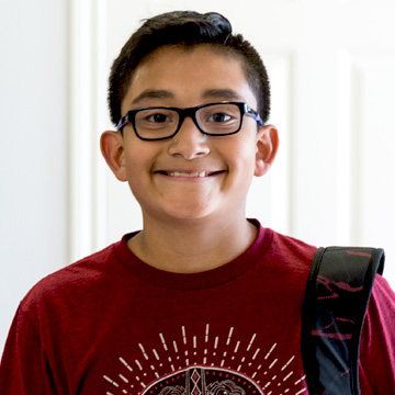 school age boy smiling with backpack on