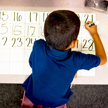 boy at table writing numbers