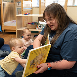 Teacher reading to babies on carpet